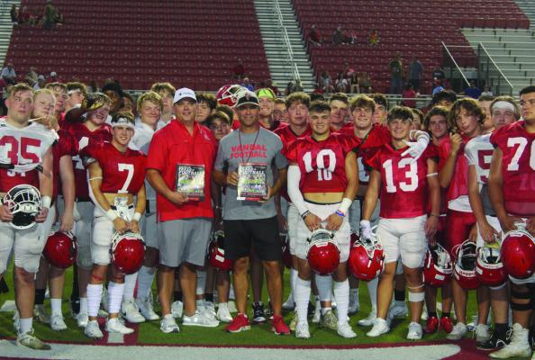 J. J. Wilson (left), representing the Canton office of Texas Farm Bureau Insurance, presented Van Vandal Head Football Coach Jared Moffatt and each of his varsity players with Van Vandal themed copies of the 2023 Dave Campbell’s Texas Football Magazine following the team’s annual Red/White football scrimmage Aug. 4 at Van’s Memorial Stadium. Texas Farm Bureau Insurance is in the process of making similar presentations to each varsity football program in Van Zandt County. Photo by David Barber