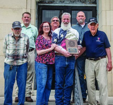 Retiring Van Zandt County Veterans Service Officer Harry Fontenot (holding plaque) stood on the front steps of the VZC Courthouse June 4 with his wife, Tonya, and well-wishers following the regular meeting of the VZC Commissioners Court. Fontenot was honored by the commissioners’ court for his 15 years of service to VZC. Photo by Faith Caughron