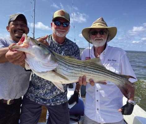 Jeff Rice, middle, shows off the big striper of the day landed with guide Lil’ Dave, left, and Bill Carey. Photo by Luke Clayton